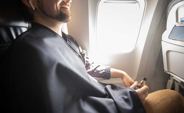 A person covered with a Shepherd's Wool Utility Cloth on a flight.